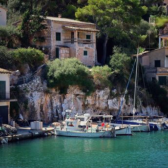 Scenic view of boats docked by rustic cliffside houses in Mallorca