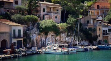 Scenic view of boats docked by rustic cliffside houses in Mallorca