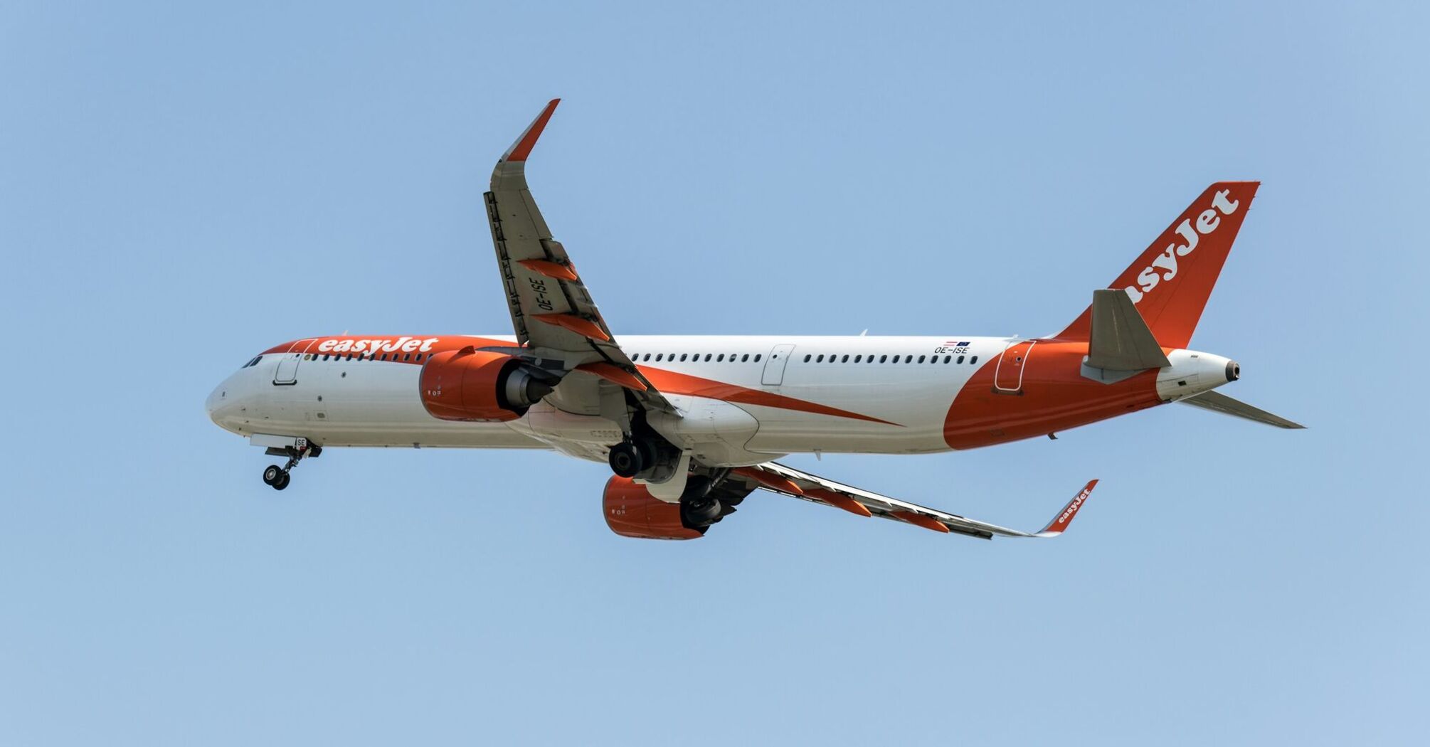 An easyJet airplane in flight against a clear blue sky