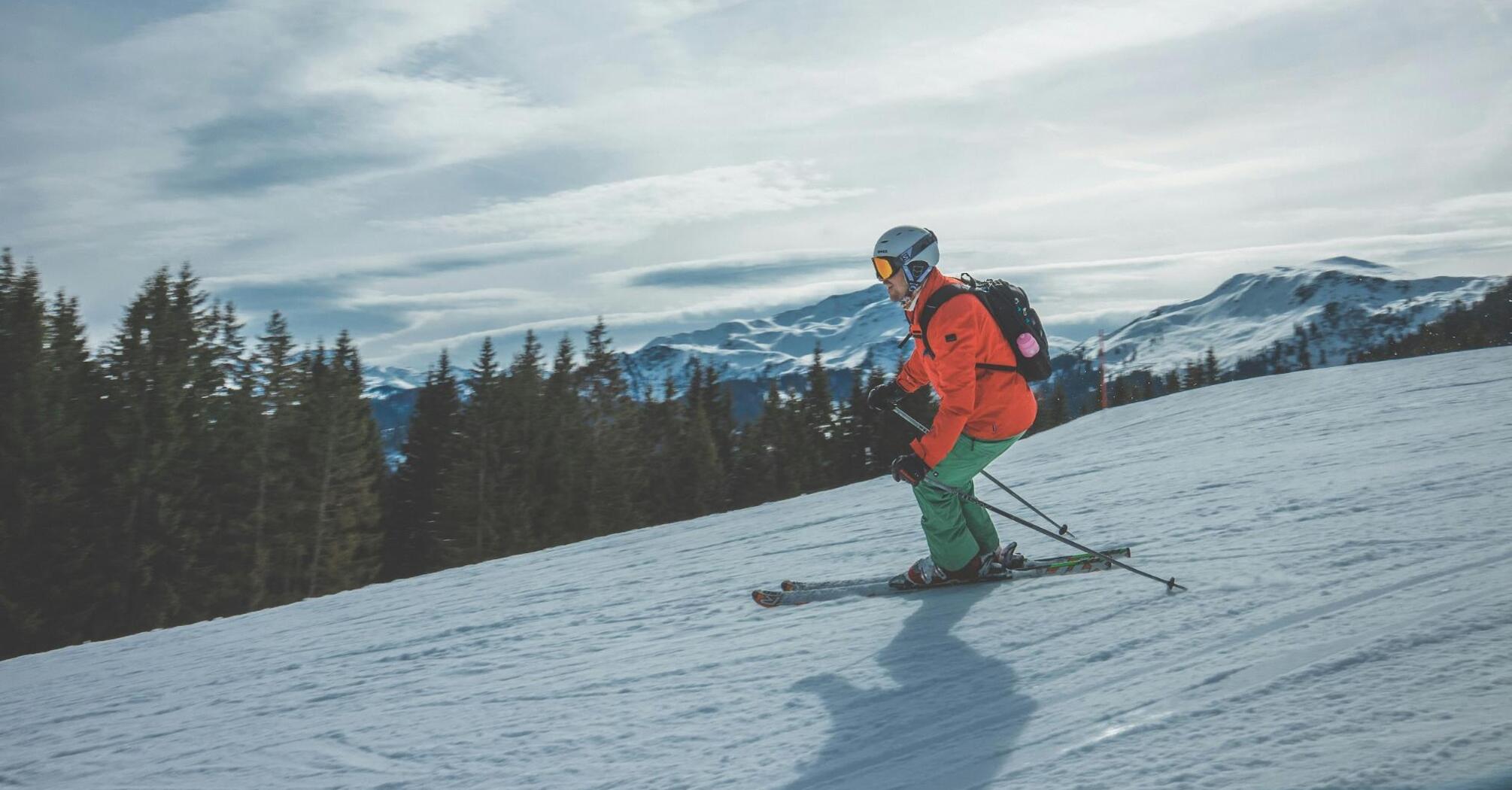 Skier navigating a snowy slope with mountains in the background