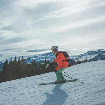 Skier navigating a snowy slope with mountains in the background