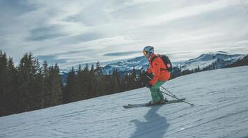 Skier navigating a snowy slope with mountains in the background
