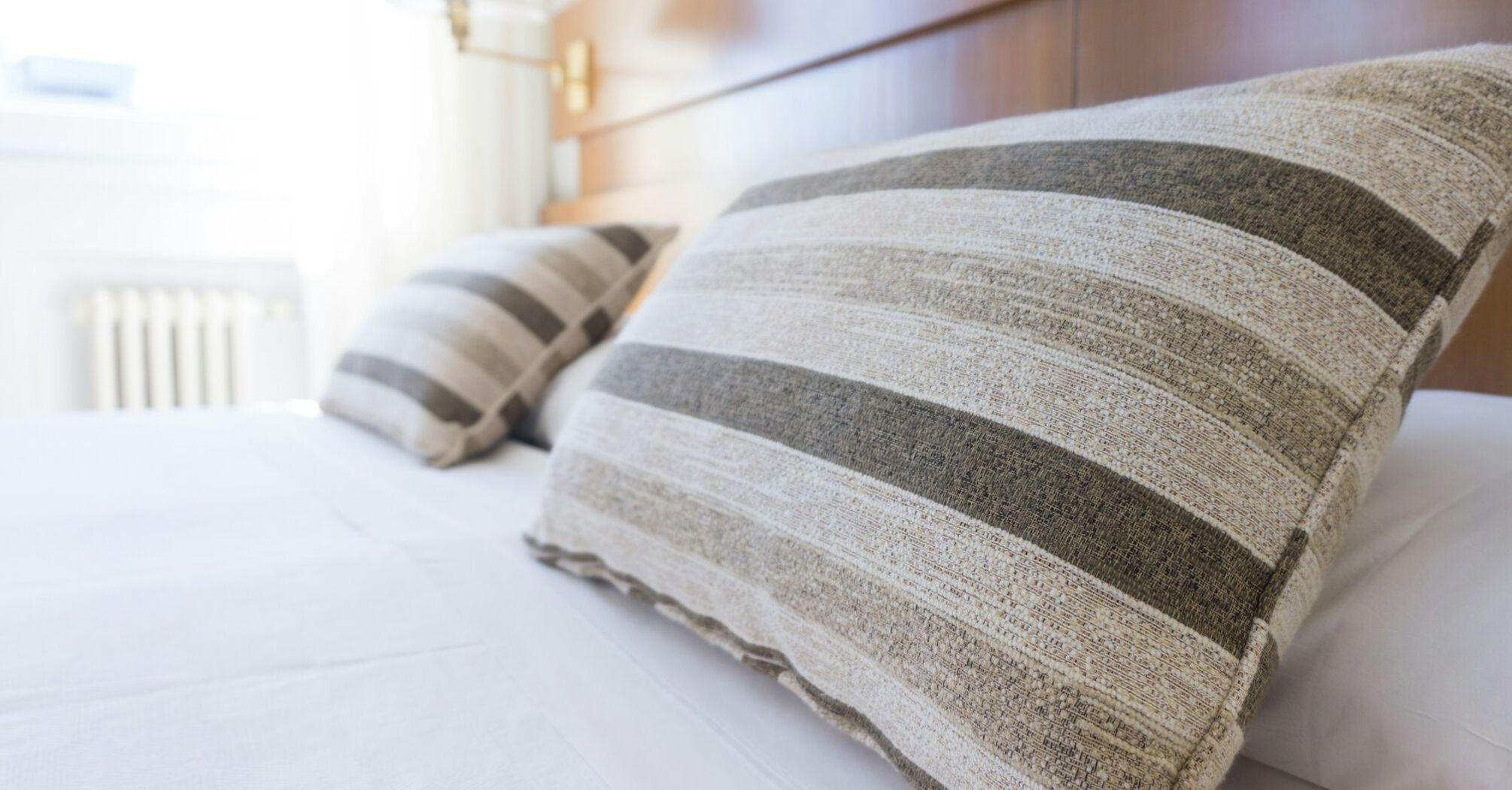 Close-up of striped pillows on a neatly made bed in a well-lit hotel room