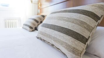 Close-up of striped pillows on a neatly made bed in a well-lit hotel room