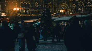 People enjoying festive lights and decorations at a Christmas market in the evening