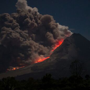 Volcano eruption with ash and lava flow at night