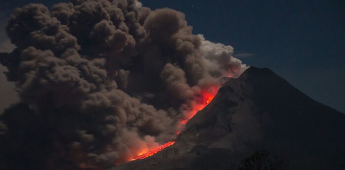 Volcano eruption with ash and lava flow at night