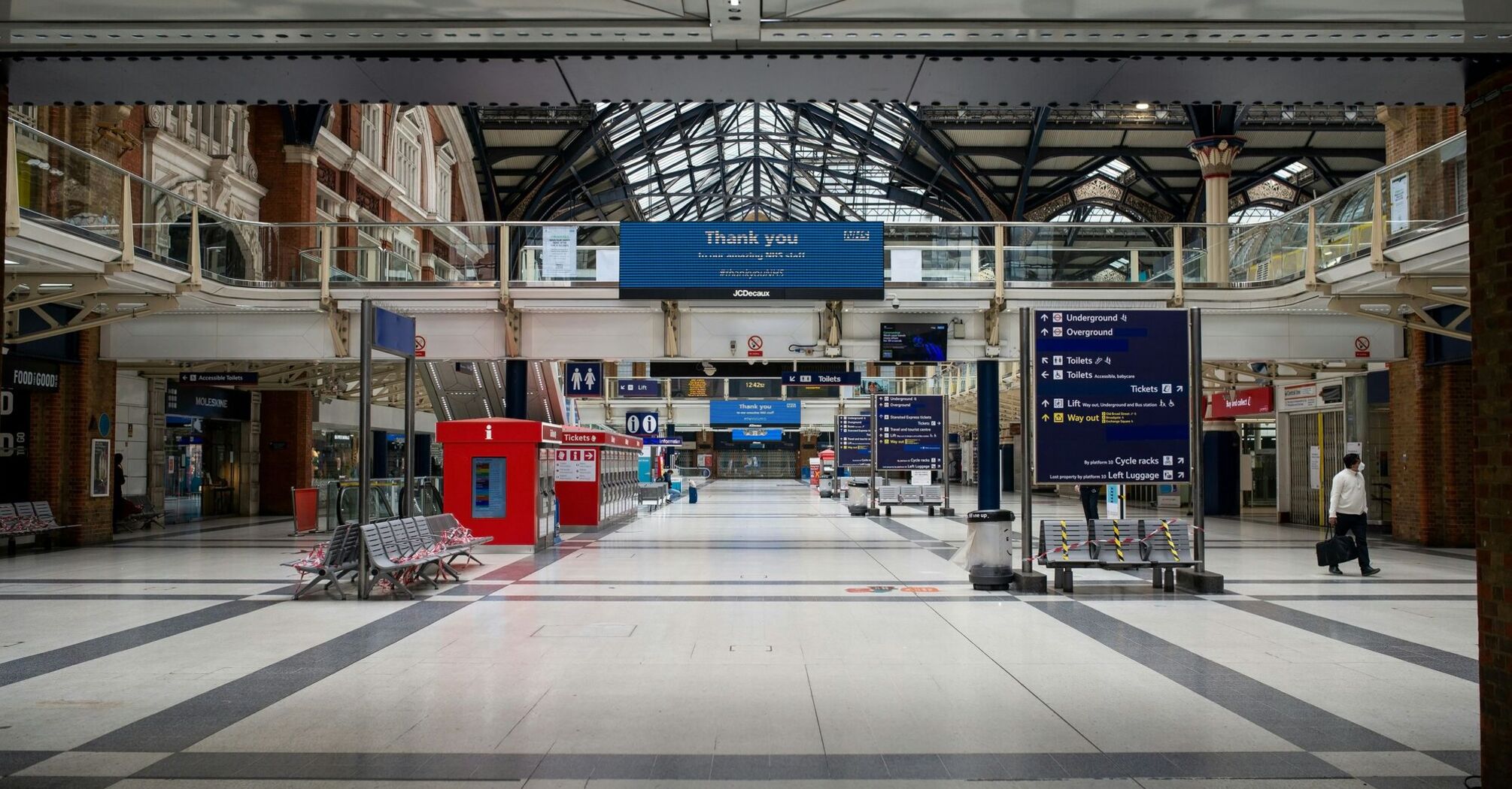 Empty concourse at Liverpool Street Station with directional signs and minimal foot traffic