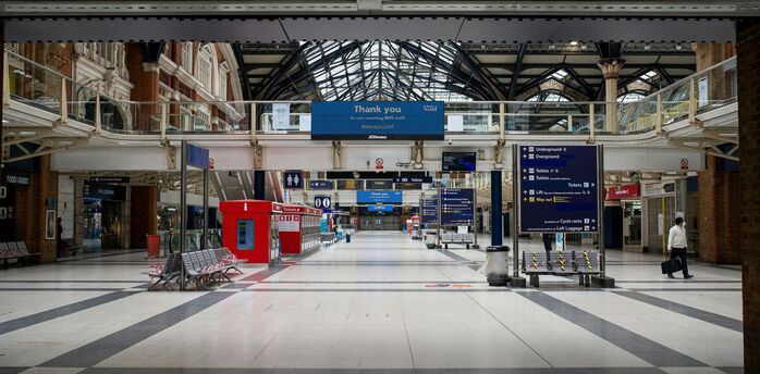 Empty concourse at Liverpool Street Station with directional signs and minimal foot traffic
