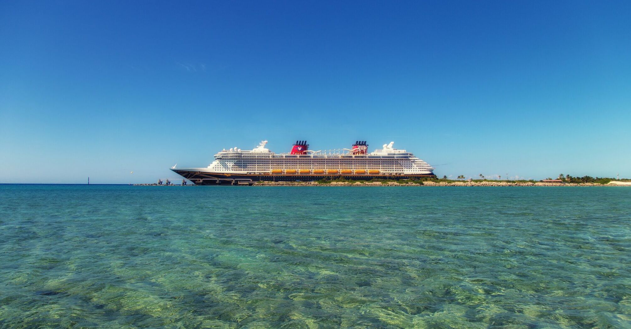 Disney cruise ship near a tropical shoreline