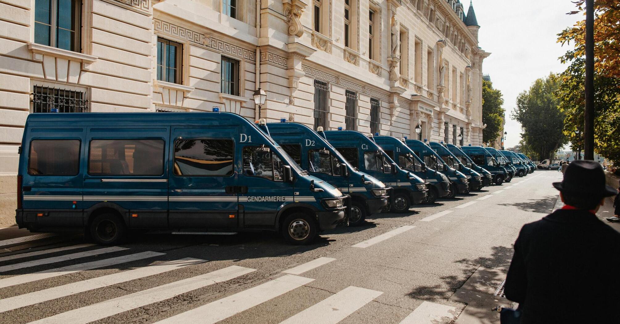 Row of police vans parked outside a historic building in Paris