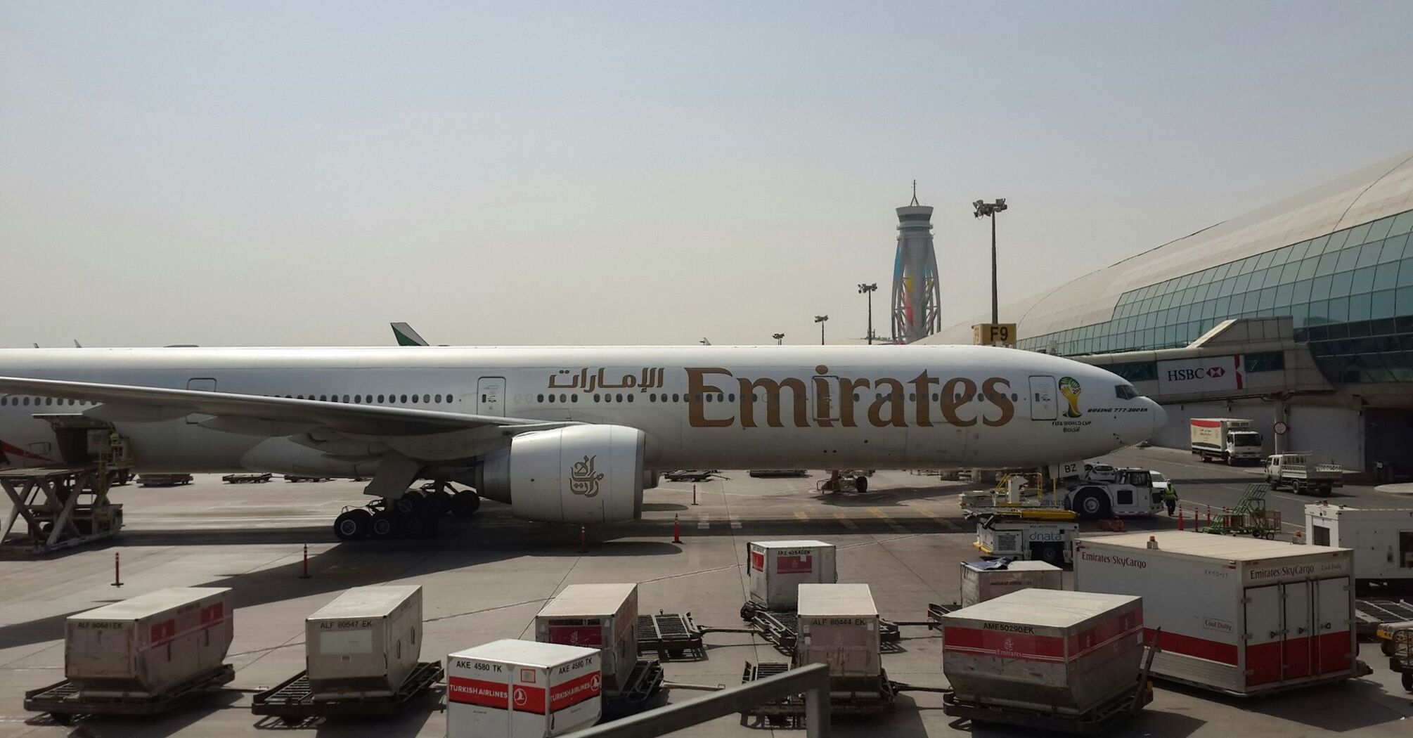 Emirates aircraft at an airport gate with cargo loading equipment nearby