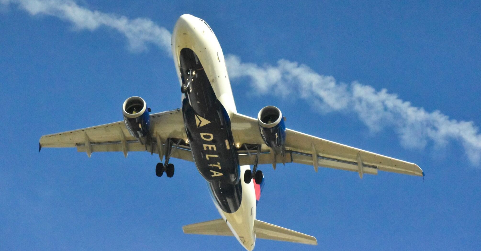 A Delta airplane ascending into a clear blue sky