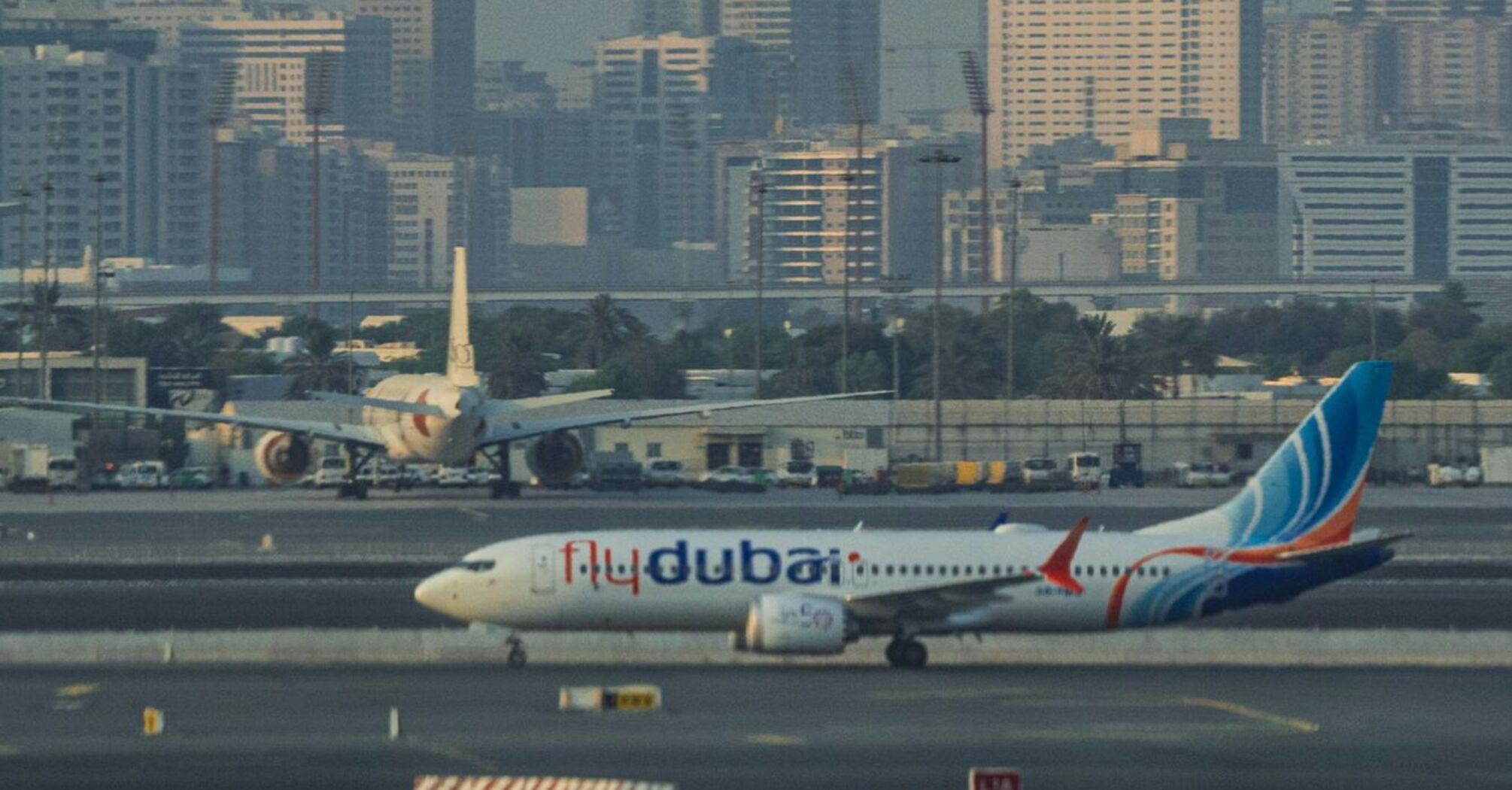 flydubai airplane taxiing on a runway with city skyline in the background