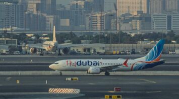 flydubai airplane taxiing on a runway with city skyline in the background