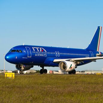 ITA Airways aircraft on runway with blue sky background