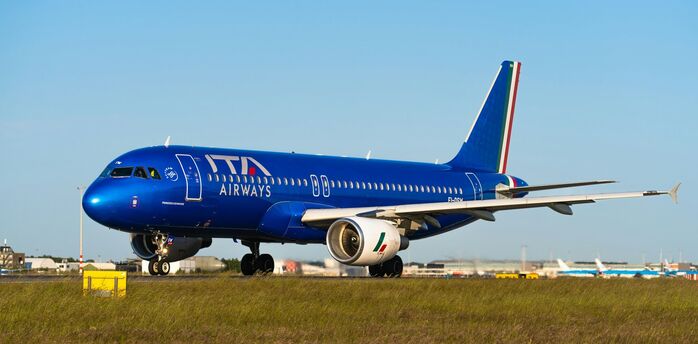 ITA Airways aircraft on runway with blue sky background
