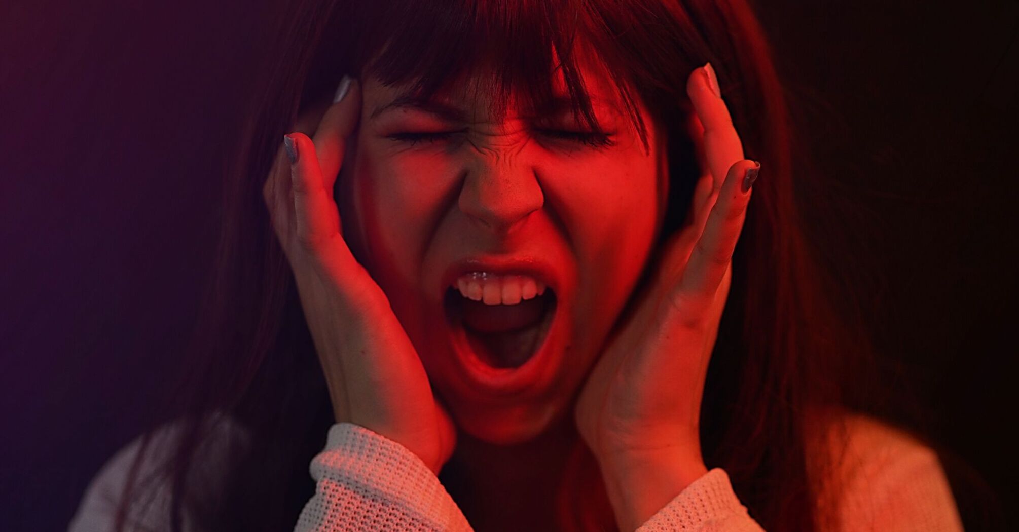 A woman screaming and holding her head in frustration