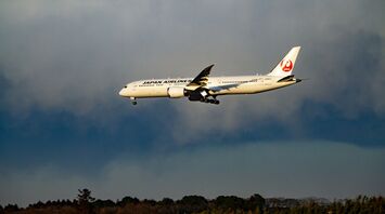 Japan Airlines plane in flight against a cloudy sky