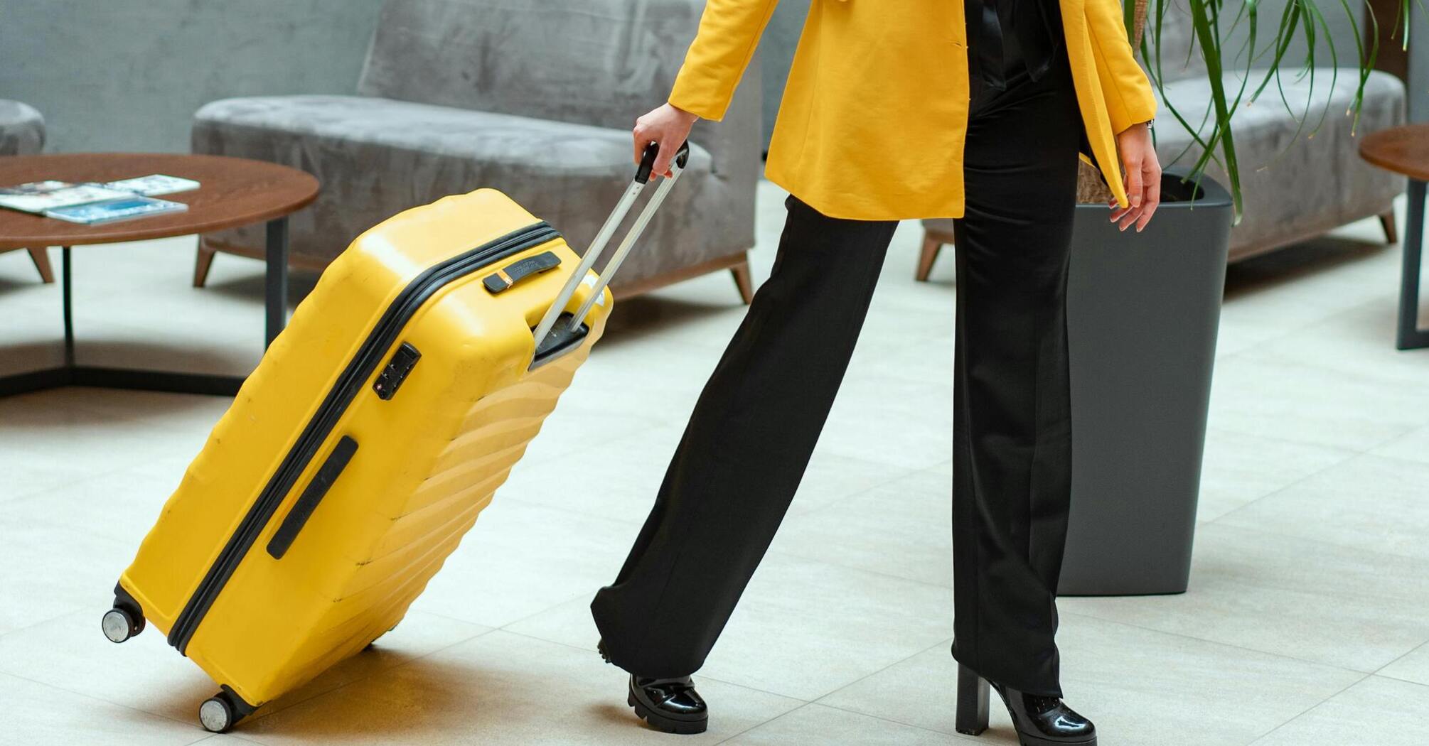 Woman in yellow coat pulling a yellow suitcase