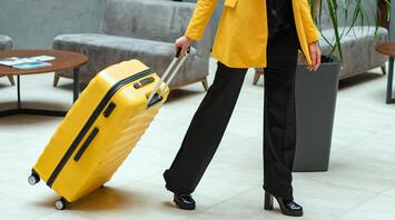 Woman in yellow coat pulling a yellow suitcase