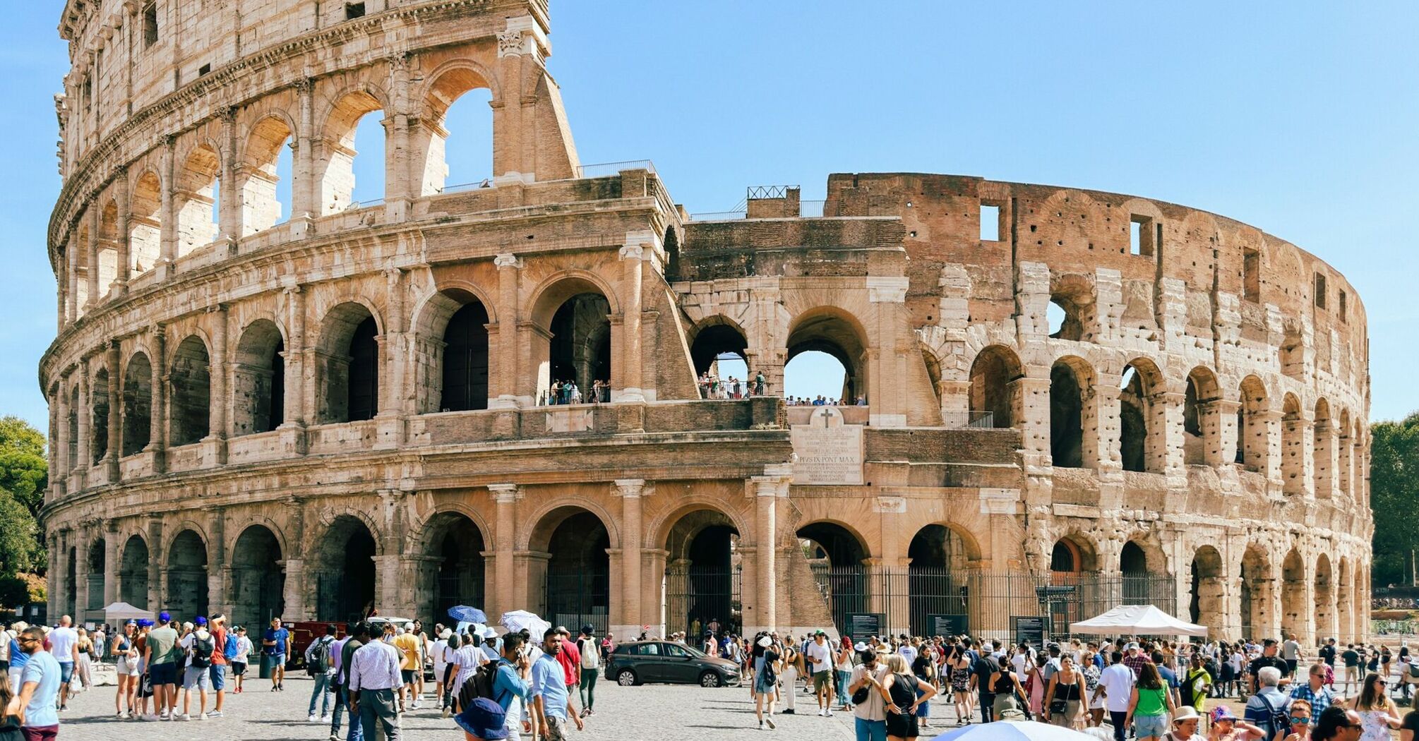 Tourists visiting the ancient Roman Colosseum under a clear blue sky