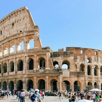 Tourists visiting the ancient Roman Colosseum under a clear blue sky