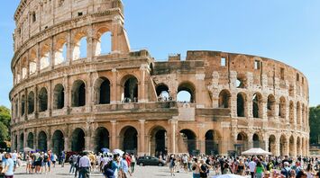 Tourists visiting the ancient Roman Colosseum under a clear blue sky
