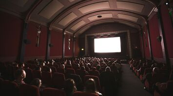 Audience seated in a classic cinema hall watching a movie on a large screen