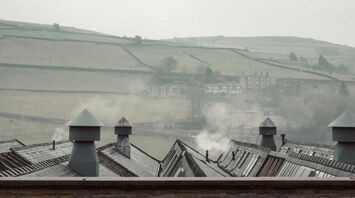 A foggy, wintry landscape with rooftops and distant hills