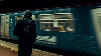 A man waits on a platform as a ScotRail train moves past