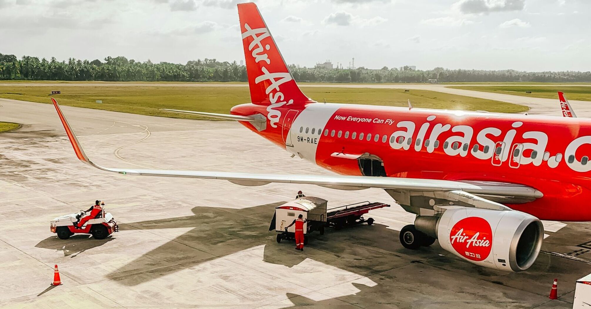 AirAsia aircraft parked on an airport tarmac with ground support vehicles nearby