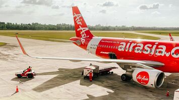 AirAsia aircraft parked on an airport tarmac with ground support vehicles nearby