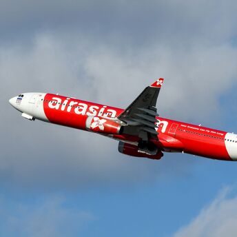 AirAsia X airplane in flight against a cloudy sky