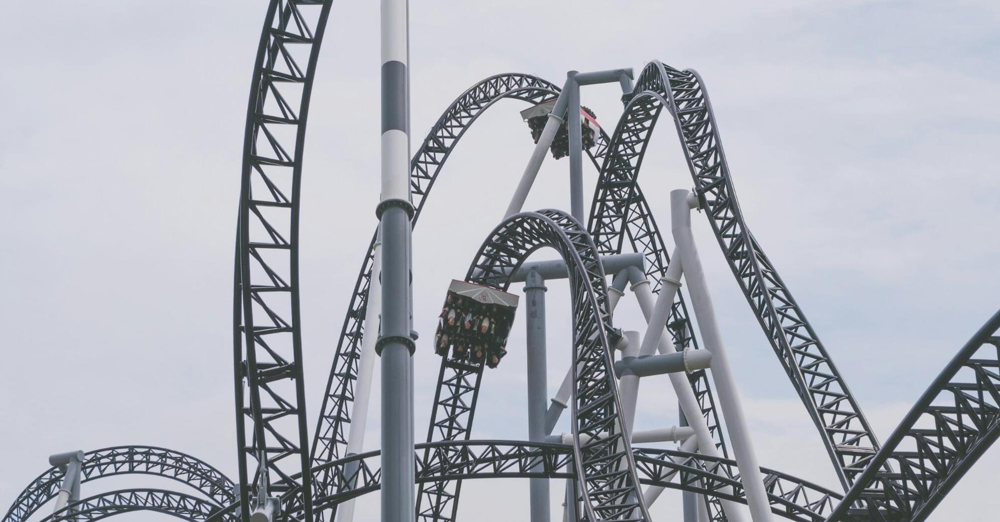 A modern steel rollercoaster with loops and twists under a cloudy sky