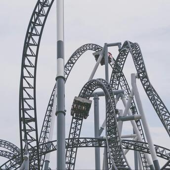 A modern steel rollercoaster with loops and twists under a cloudy sky