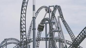A modern steel rollercoaster with loops and twists under a cloudy sky
