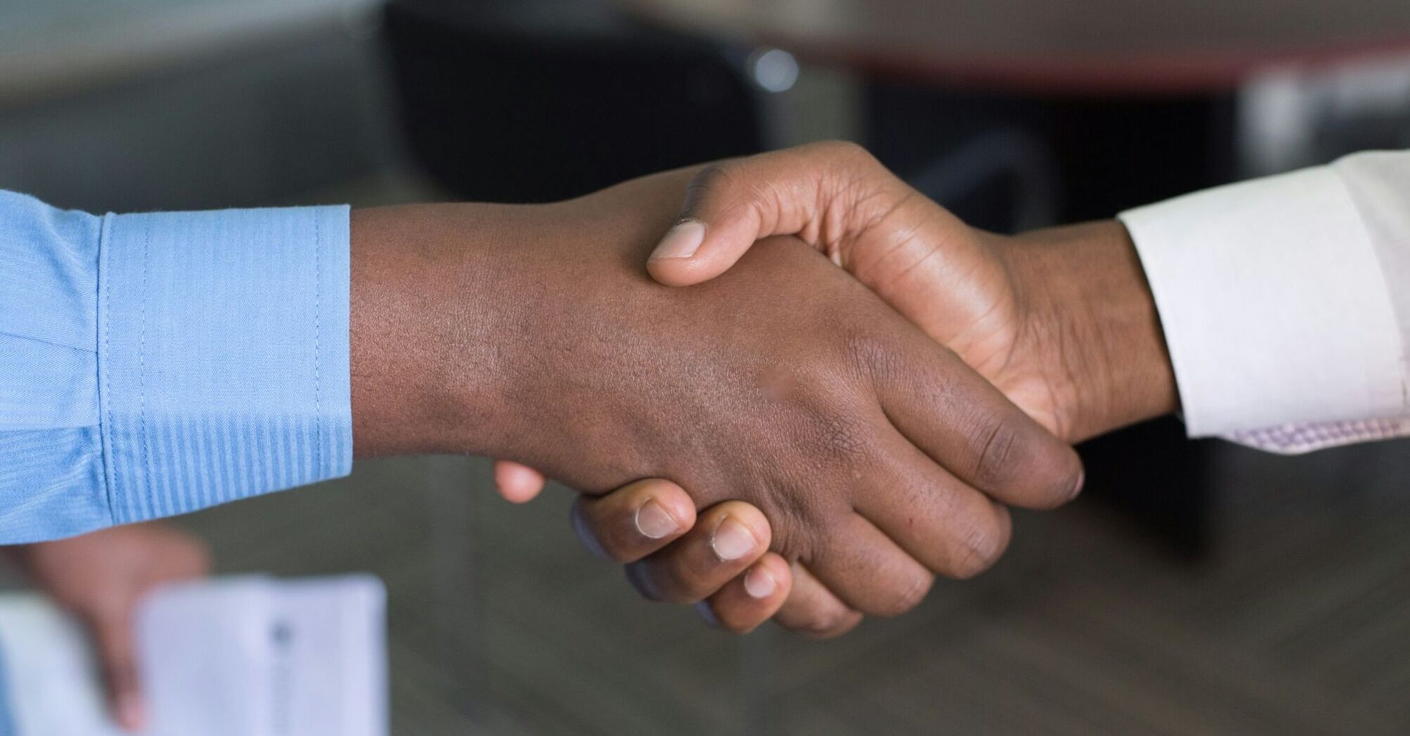 Close-up of two individuals shaking hands in a formal setting