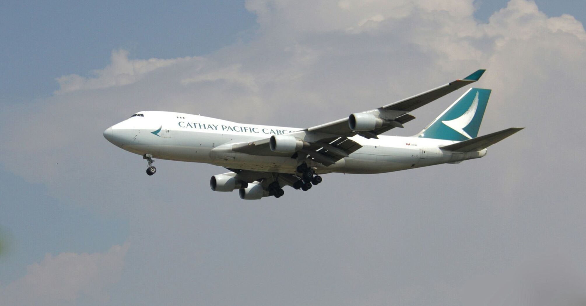 Cathay Pacific airplane flying under cloudy sky