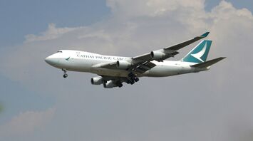 Cathay Pacific airplane flying under cloudy sky