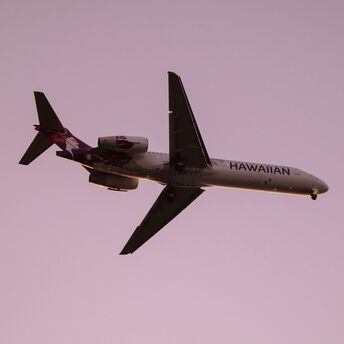 Hawaiian Airlines plane in flight at sunset