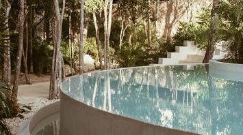 Modern circular pool surrounded by lush forest greenery
