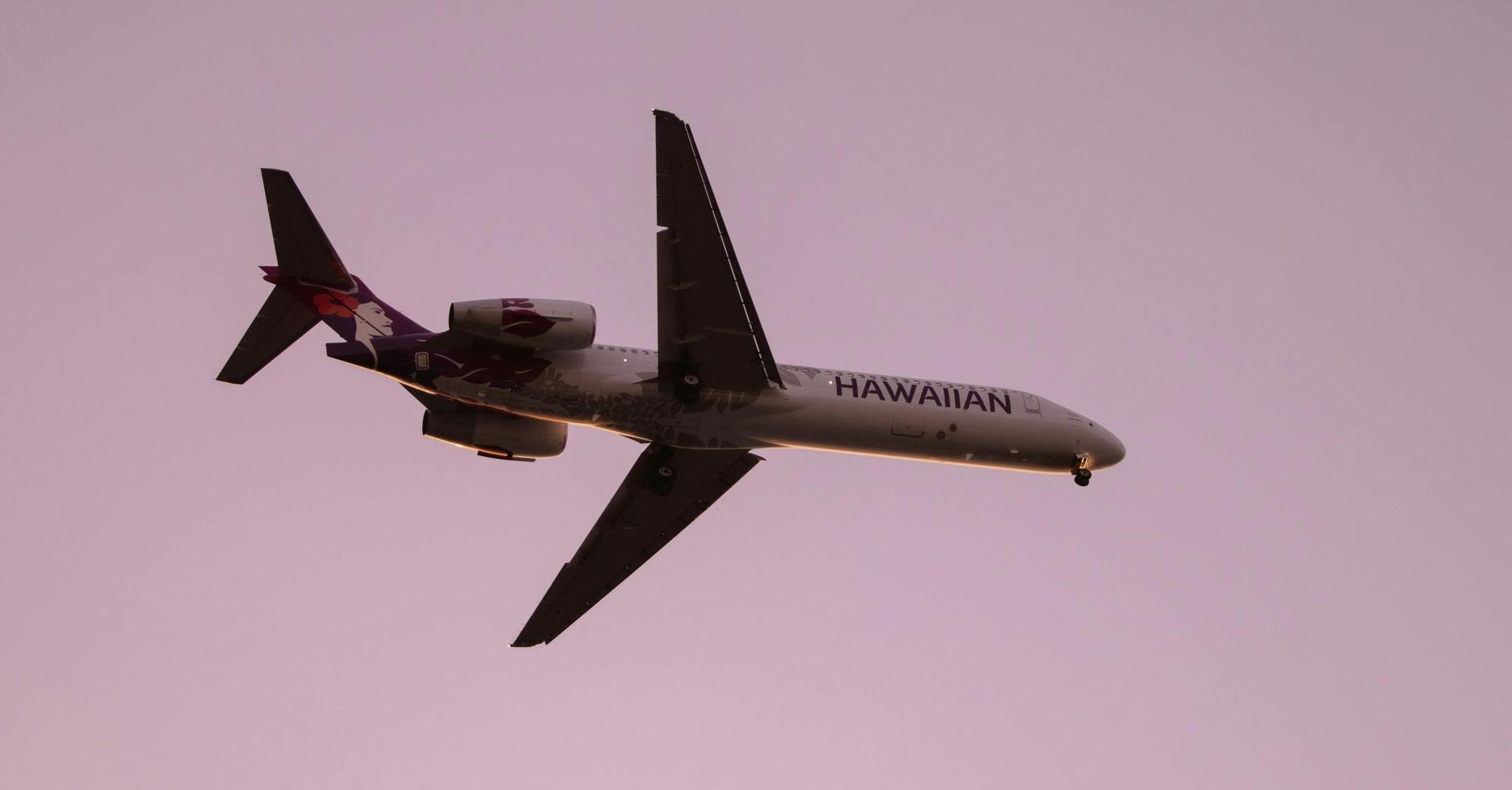 Hawaiian Airlines plane flying against a sunset sky