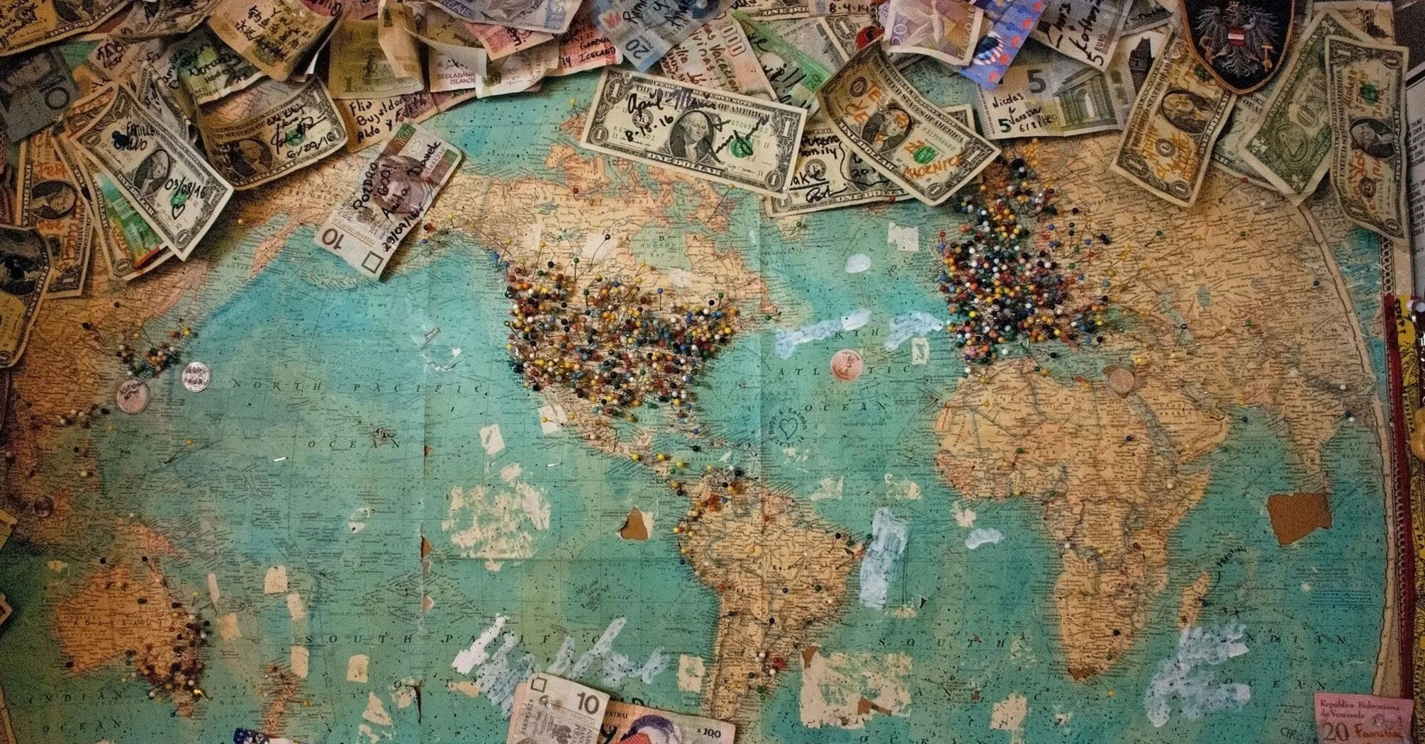 World map with various international currencies and pins marking travel destinations