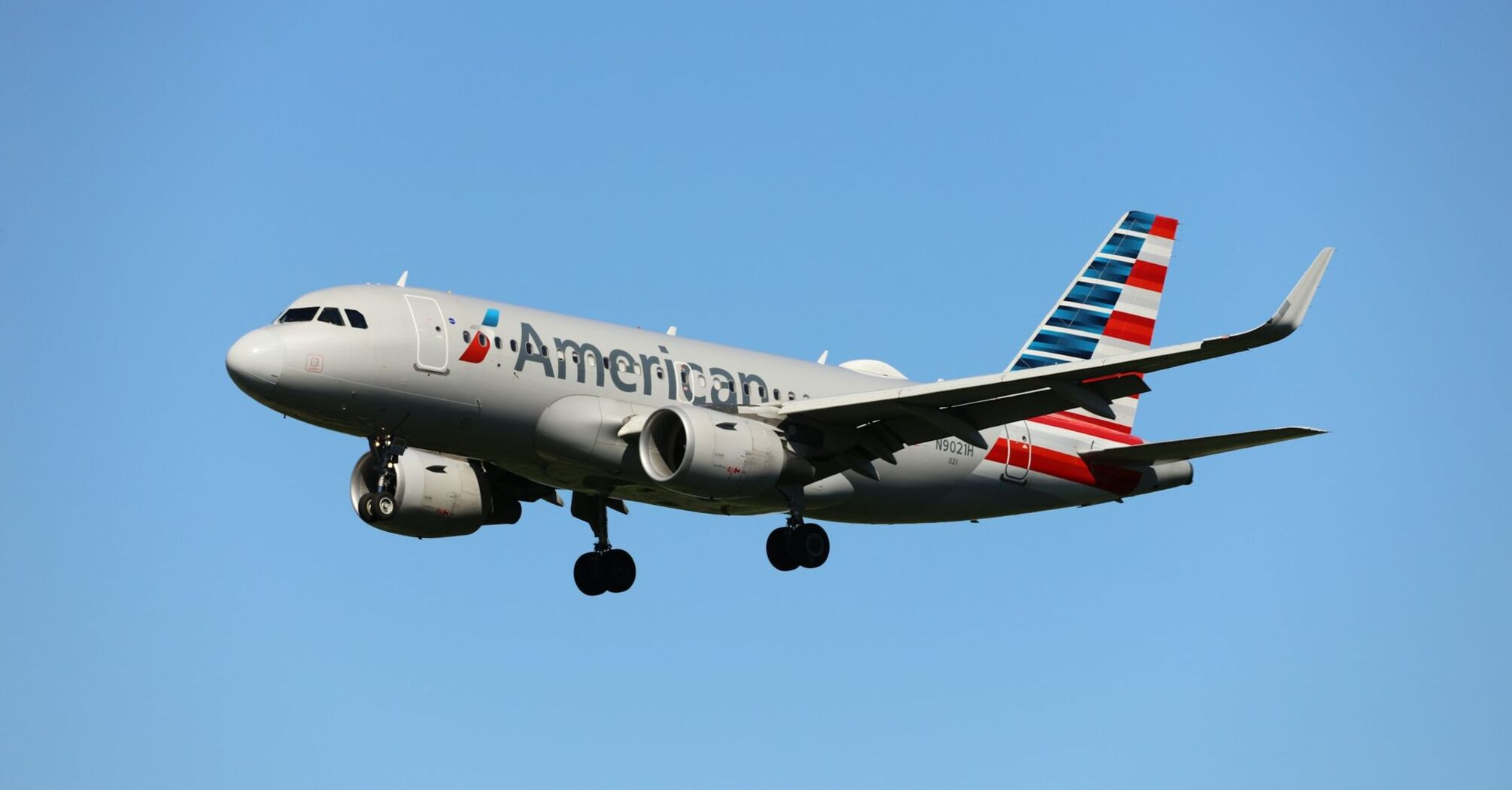 American Airlines plane in flight against a clear blue sky