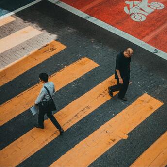Two people crossing a striped crosswalk viewed from above