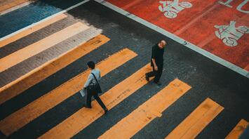 Two people crossing a striped crosswalk viewed from above