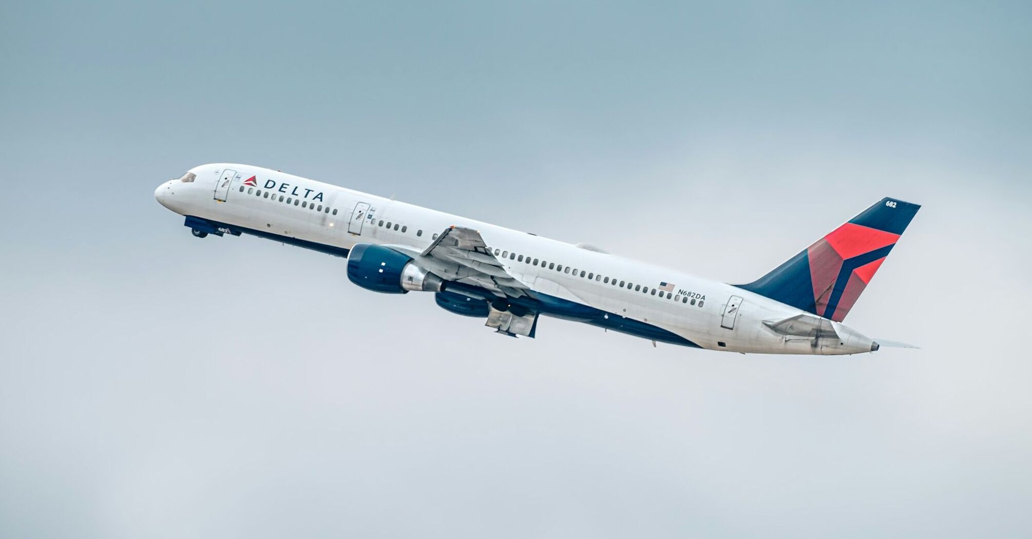 Delta Airlines aircraft ascending against a cloudy sky