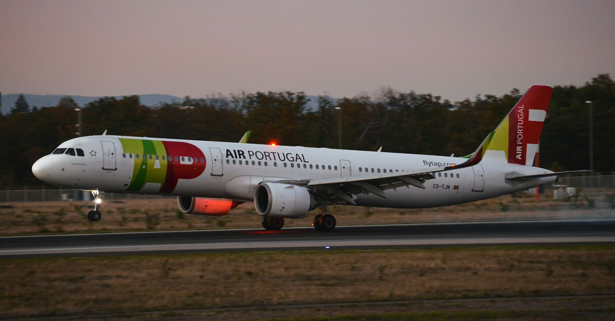 TAP Air Portugal aircraft landing on a runway at dusk