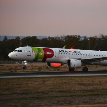 TAP Air Portugal aircraft landing on a runway at dusk
